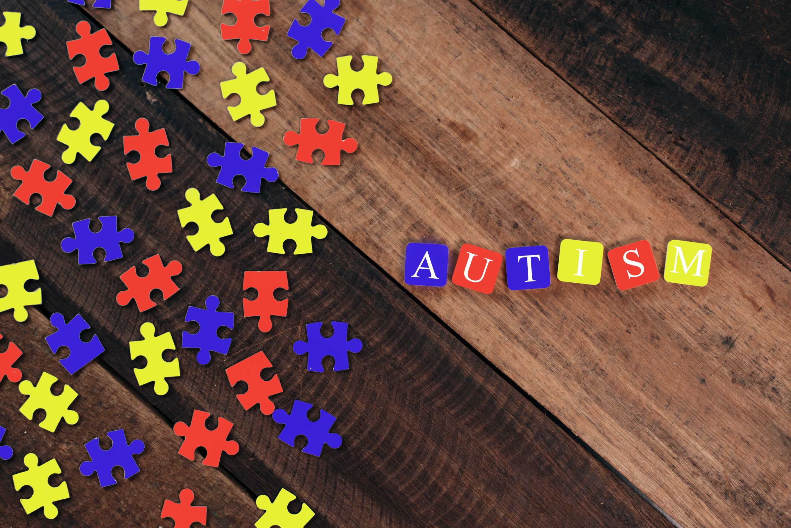 Colourful jigsaw puzzle and alphabet tiles with AUTISM word. Autism concept